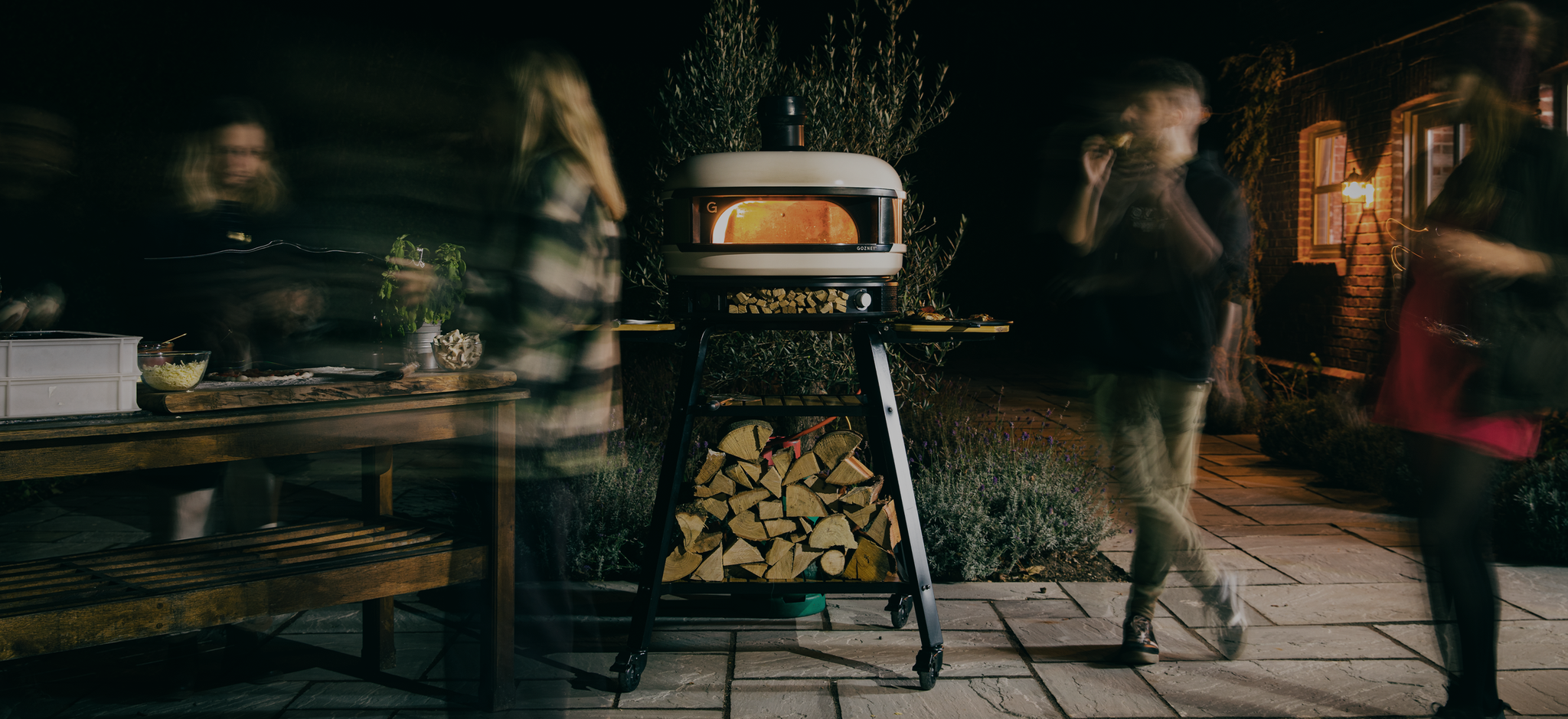Night time pizza party with lit pizza oven