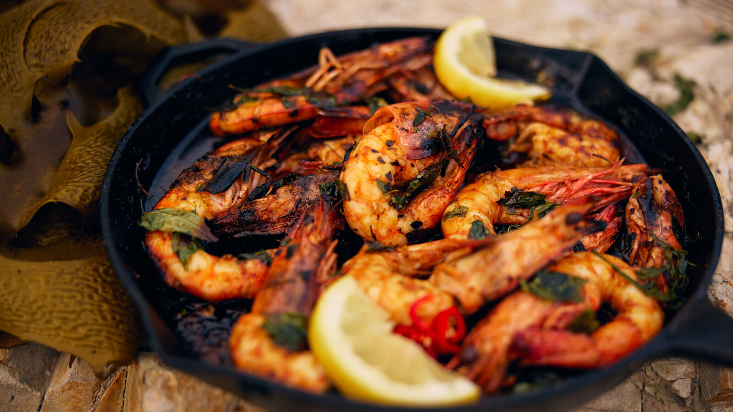 Prawns with lemon in a cast iron pan on the beach