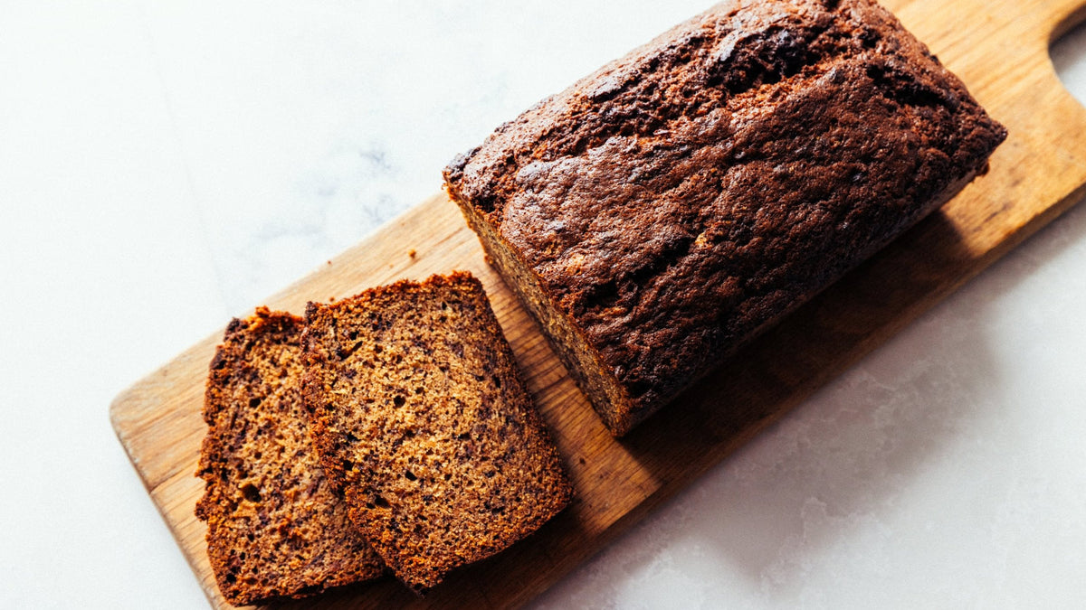 Wood-fired Banana Bread with two slices cut out on a board. recipe poster image